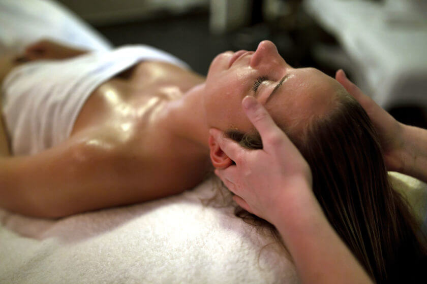 Eine auf dem Rücken liegende Frau erhält eine Kopfmassage