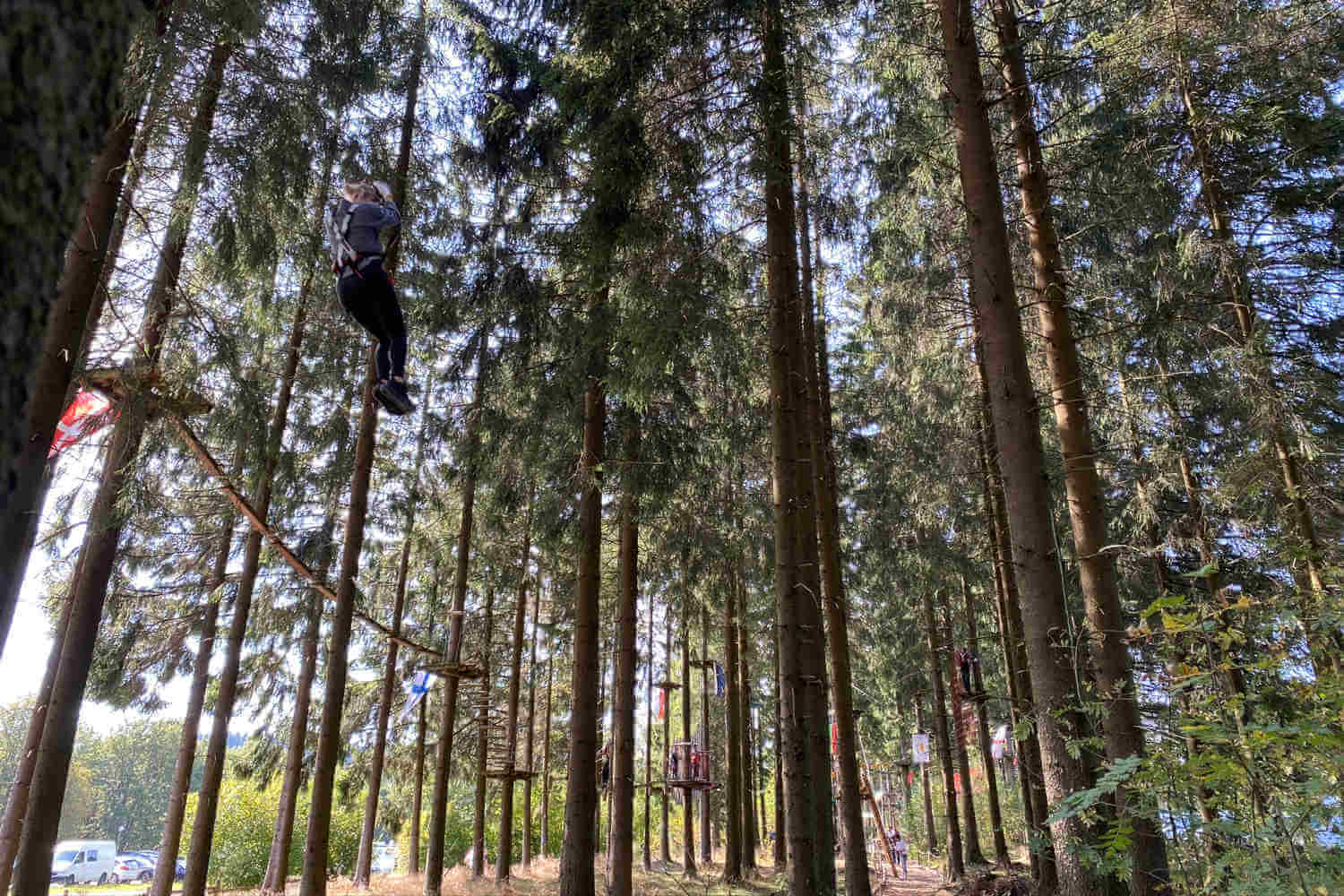 Frau fliegt am Stahlseil zwischen Bäumen im Kellerwald Winterberg