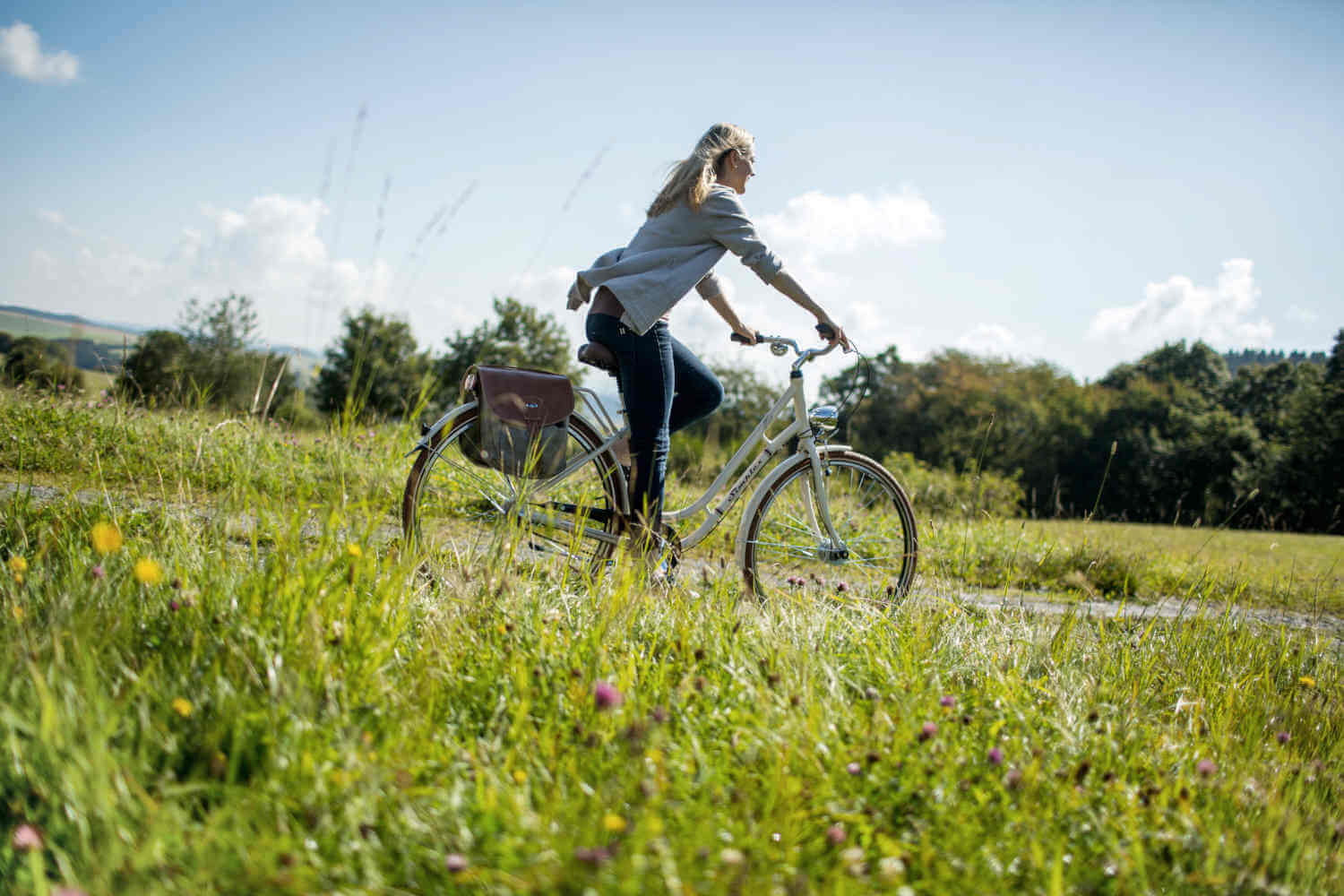 Eine Frau fährt auf dem Fahrrad über den sommerlichen Feldweg