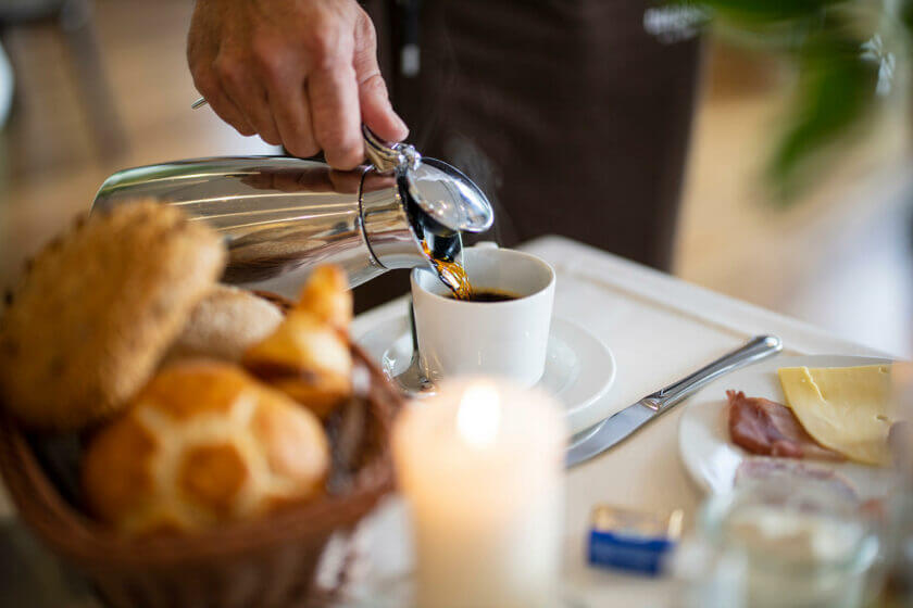 Am Frühstückstisch wird Kaffee aus der Kanne in die Tasse eingeschenkt - Hotel Diedrich