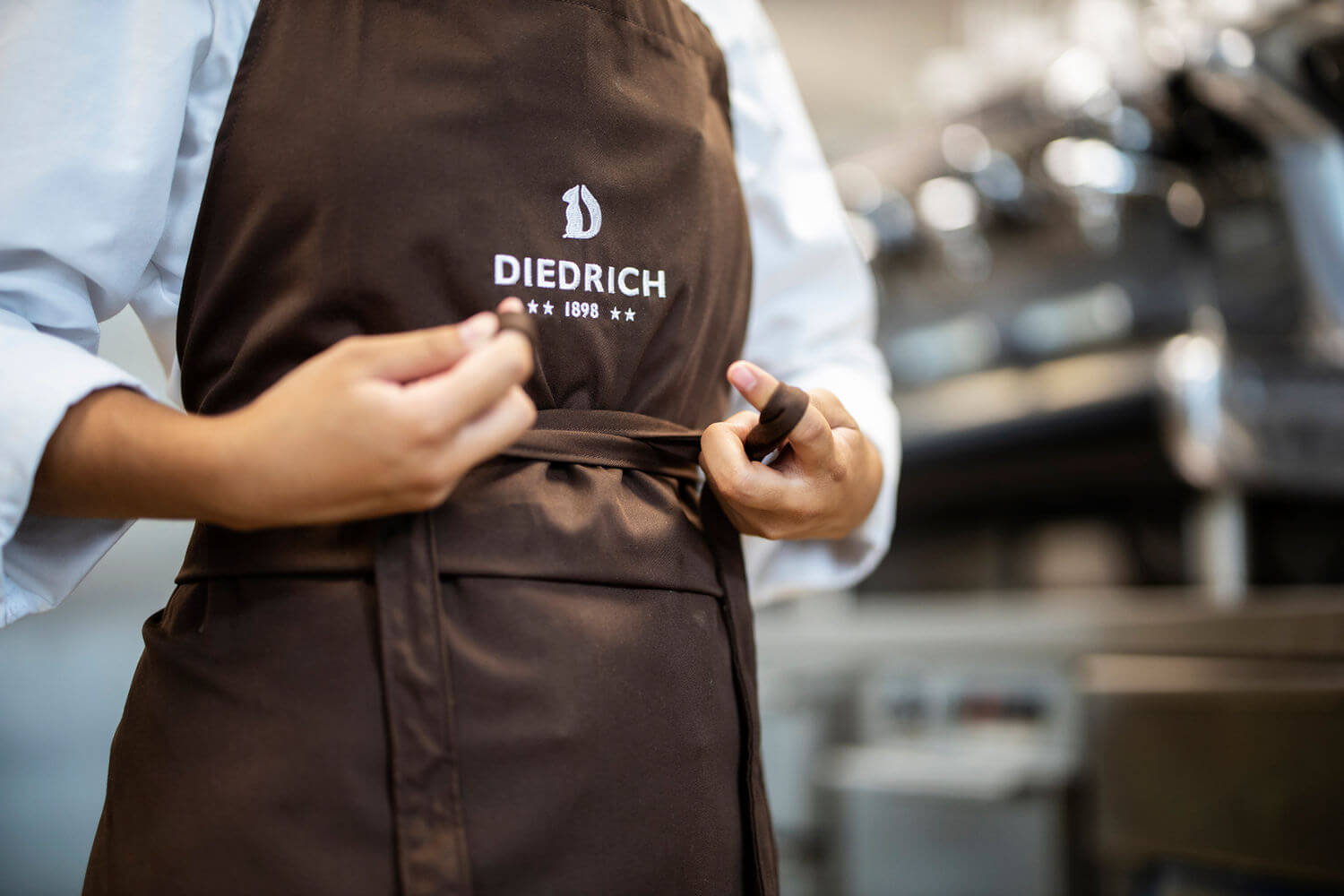 Eine Kochschürze mit Hotel Diedrich Logo wird umgebunden