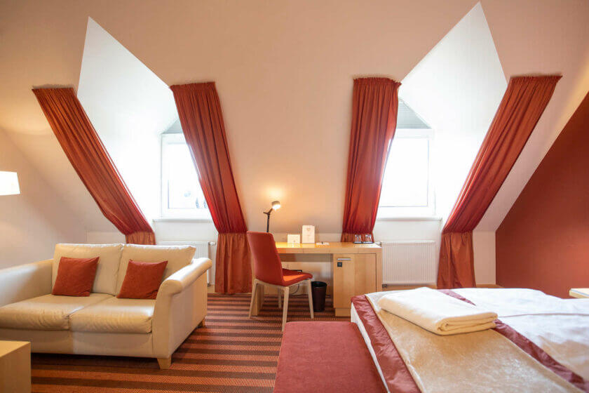 Blick auf Sofa, Schreibtisch und Bett im hellen Doppelzimmer "Lichtflügel A Straßenseite" im Hotel Diedrich, Hallenberg im Sauerland
