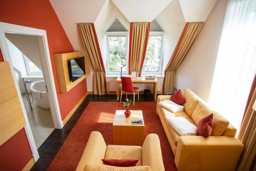 Blick auf den Sitzbereich und ins Badezimmer in der "Panorama-Suite 229 Talseite" im Hotel Diedrich, Sauerland