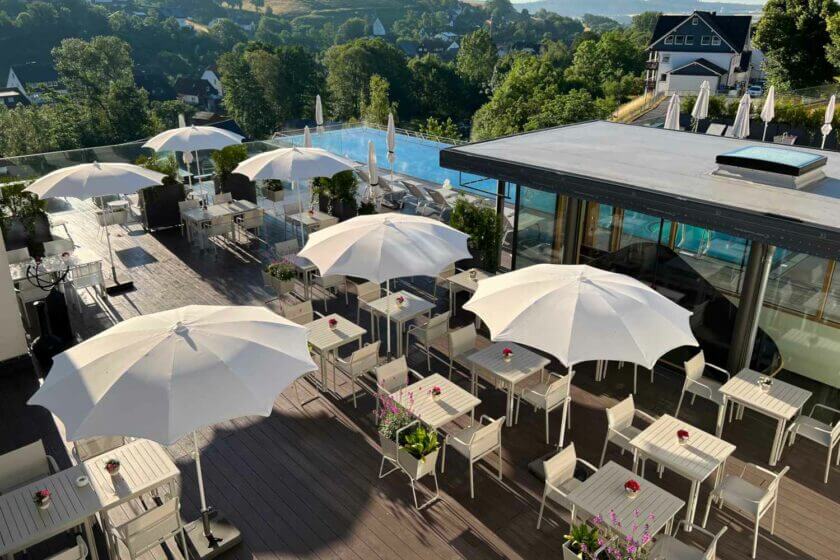 Hotel Diedrich Terrasse mit Tischen, Sonnenschirmen und Außenpool