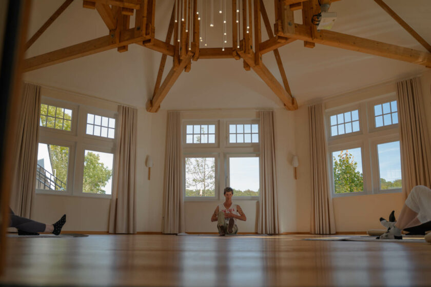 Der Yogalehrer sitzt im Yogahaus auf dem Boden und leitet eine Yogaeinheit an