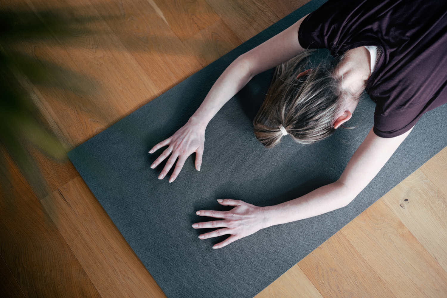 Eine Frau hat ihre Arme auf der Yogamatte vor sich ausgestreckt und streckt den Rücken durch