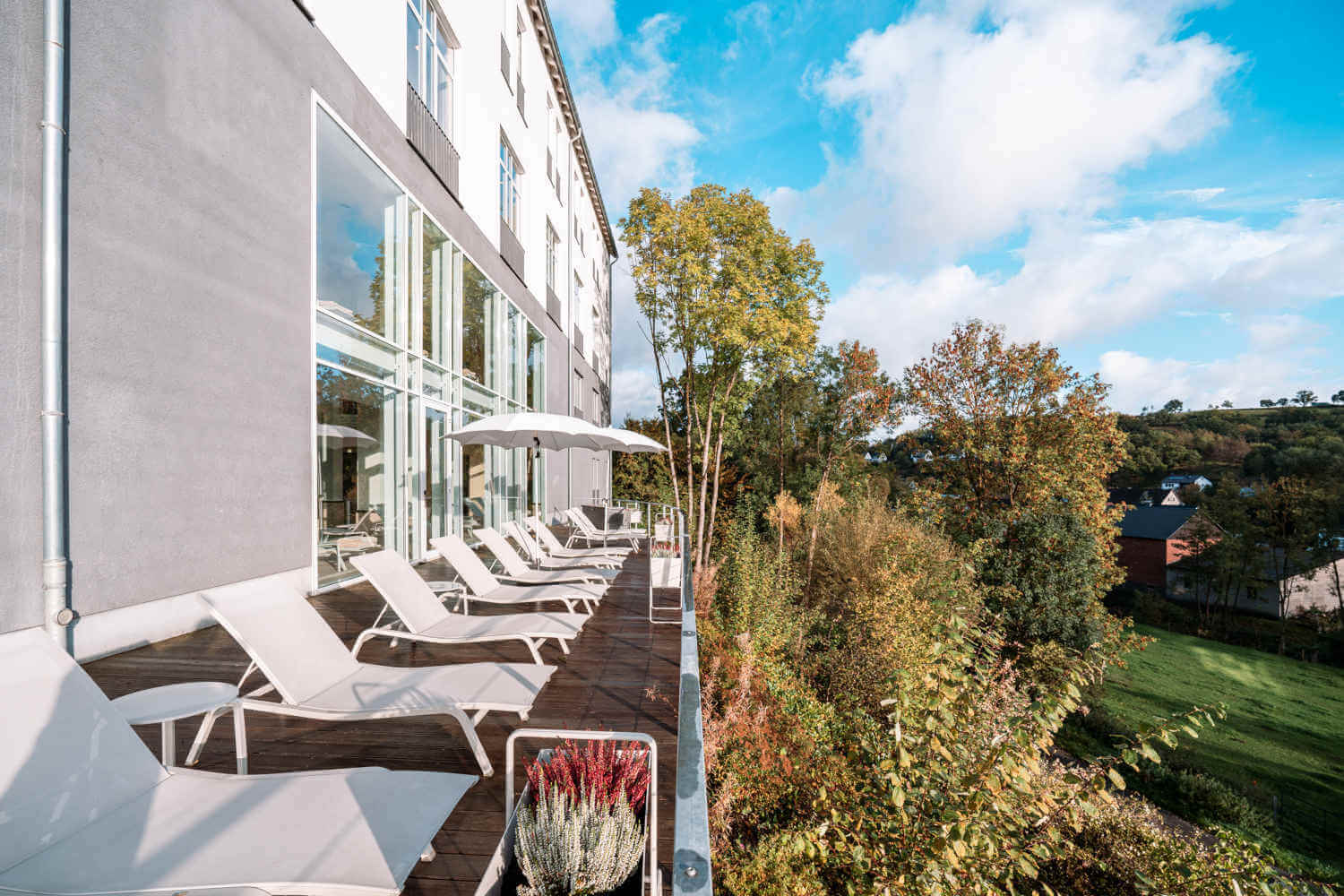 Wellnessphilosophie 4 Shot of the outdoor sunbathing terrace in front of the large panoramic windows of the indoor pool at Hotel Diedrich