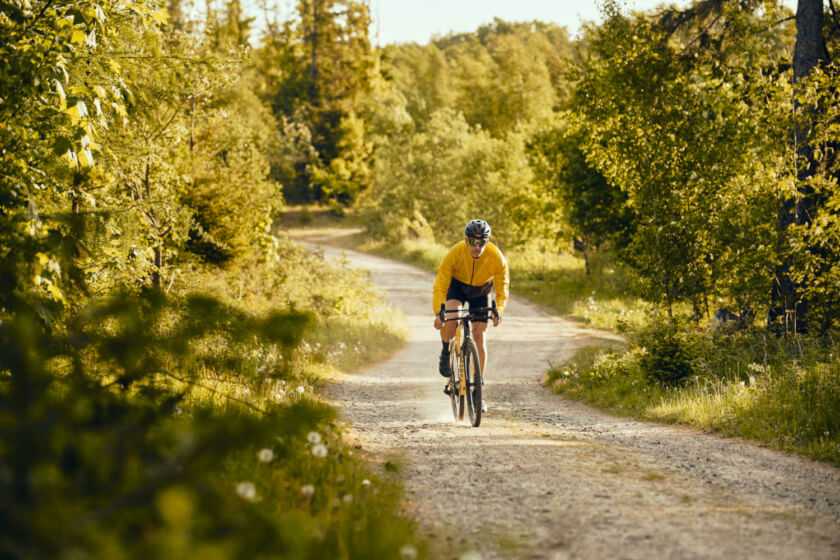 Ein Radfahrer fährt ünber den Feldweg durch die grüne Naturlandschaft