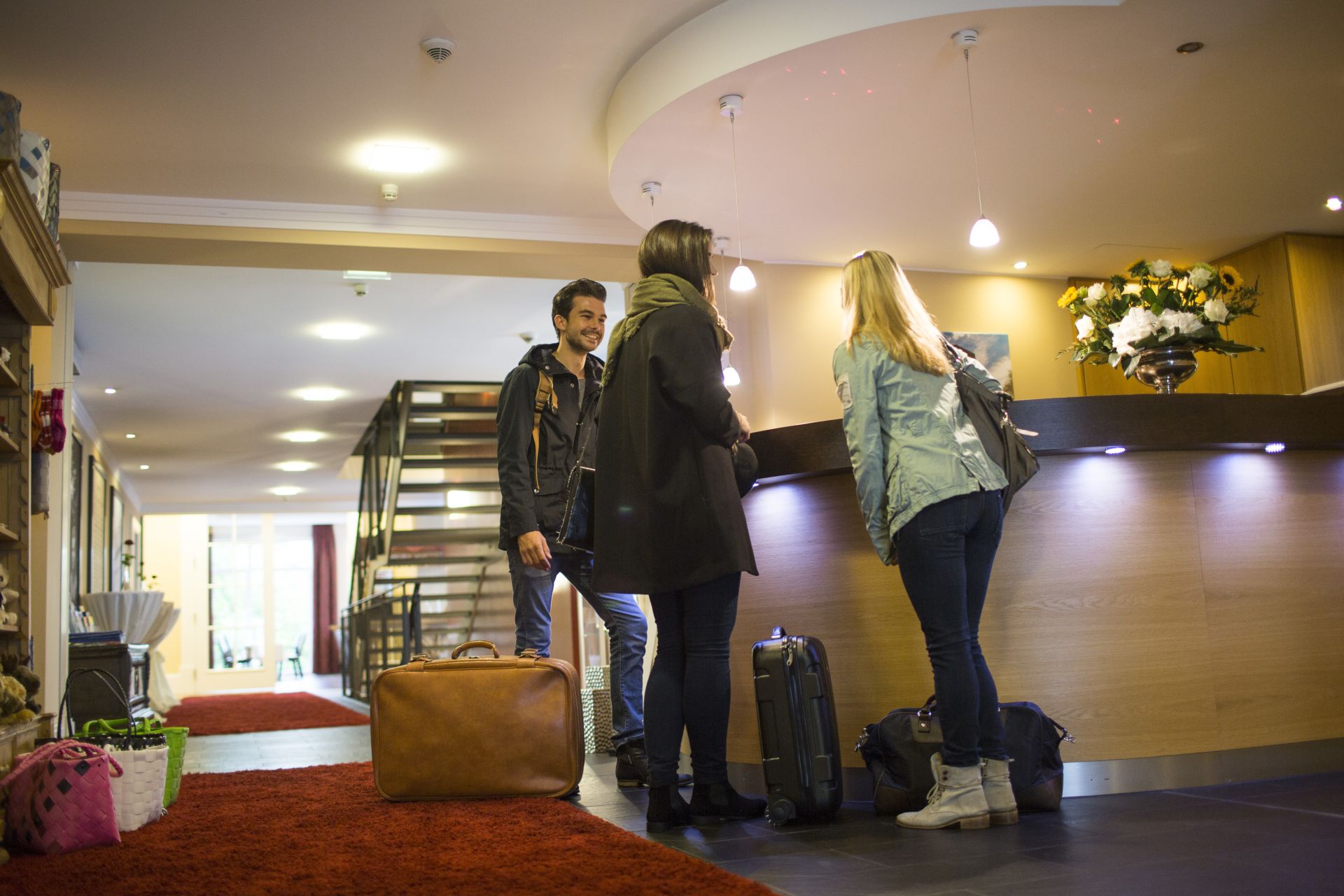 Drei Gäste mit Koffern beim Check-in an der Rezeption im DIEDRICH Wellnesshotel & Spa in Hallenberg im Sauerland