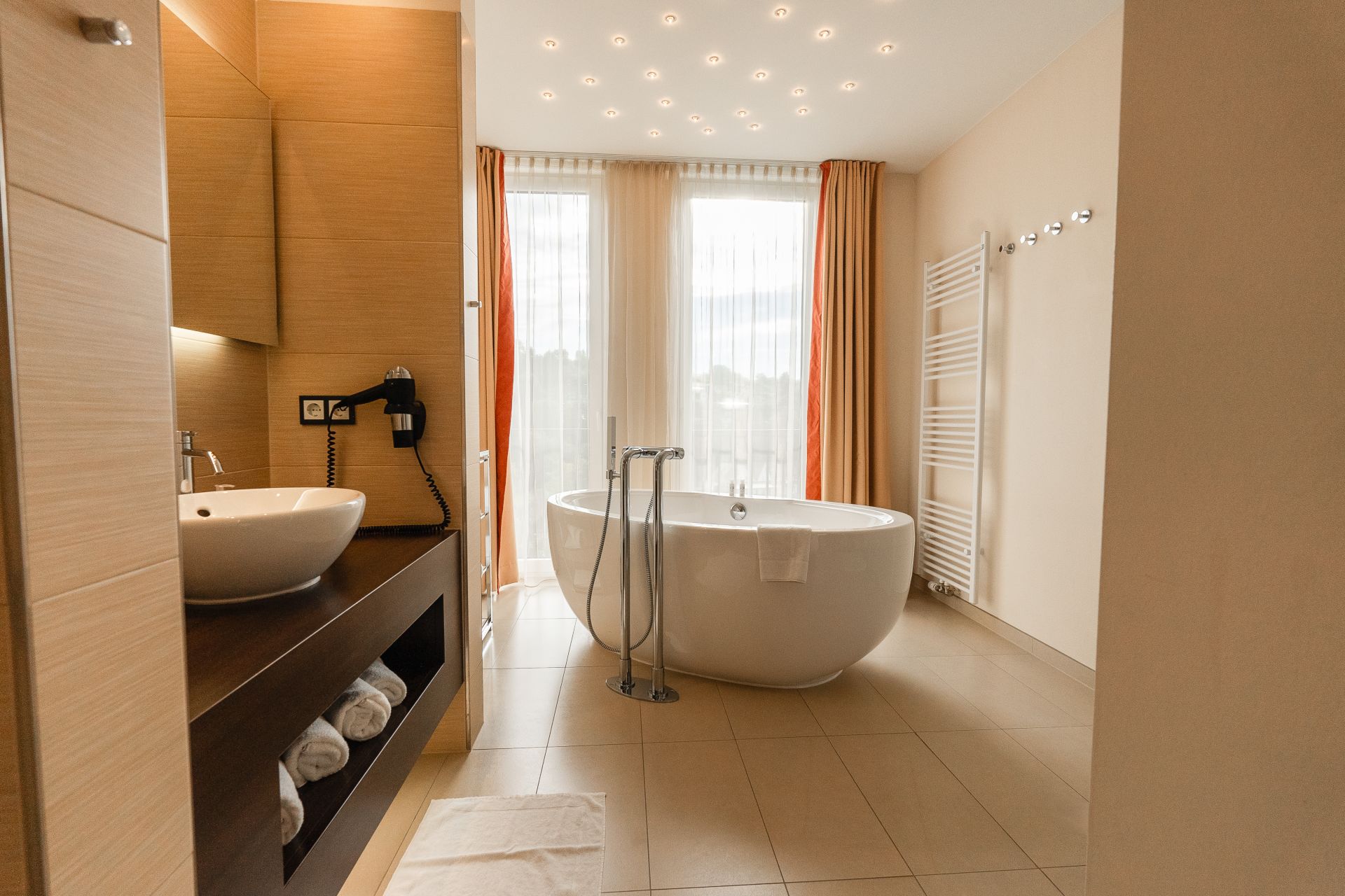 Freistehende Badewanne am Fenster im modernen Bad der Panoramasuite