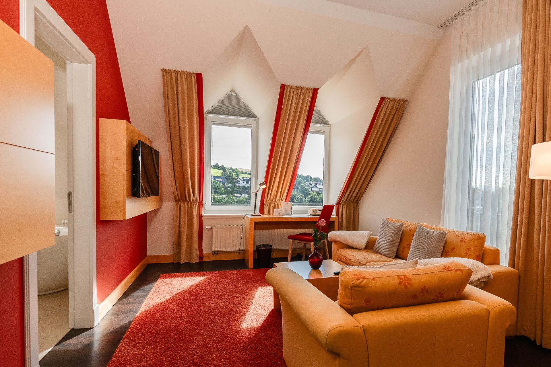 Wohnbereich der Panoramasuite mit Dachschräge, Giebelfenstern und Sofa