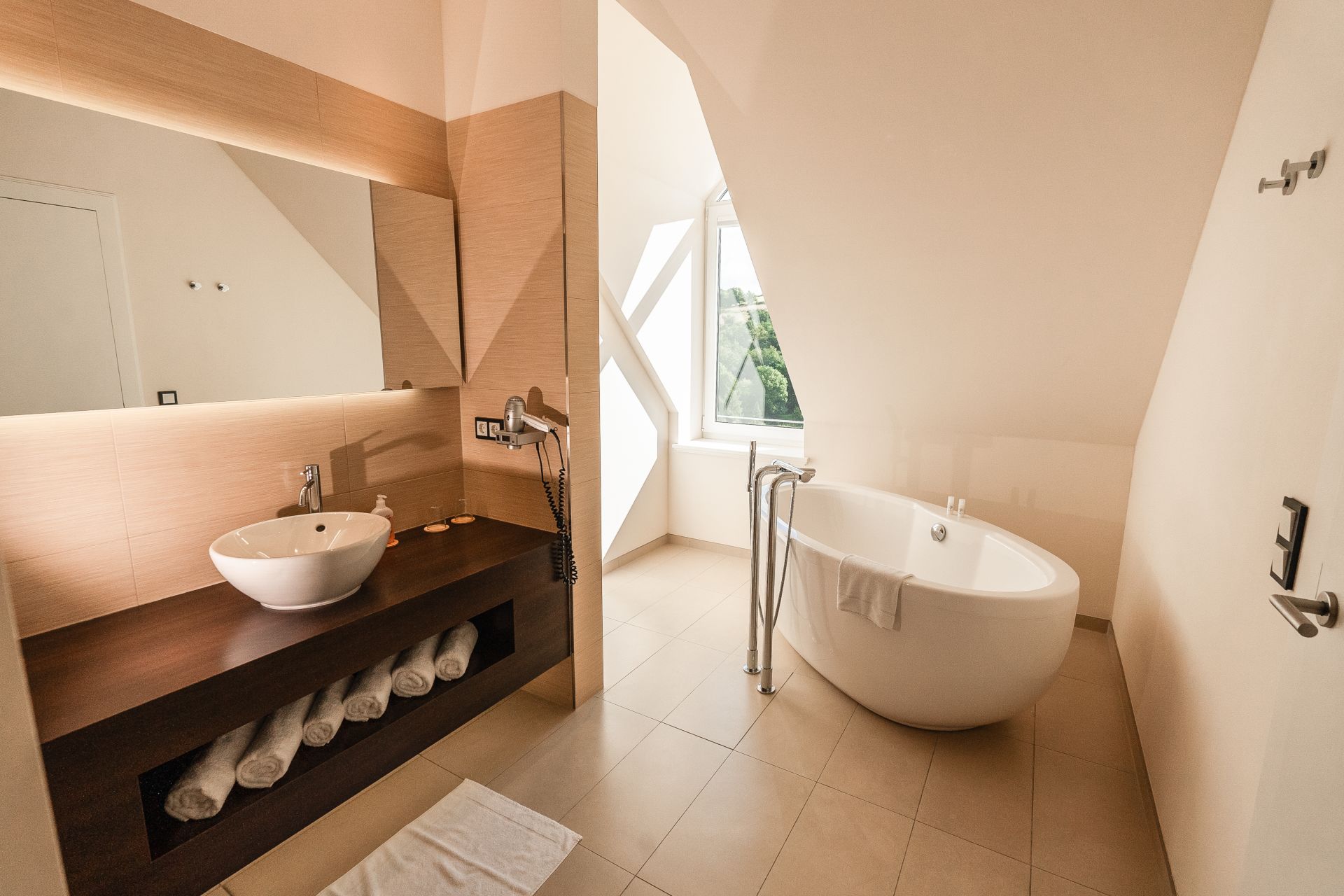 Freistehende Badewanne unter der Dachschräge im Bad der Panoramasuite